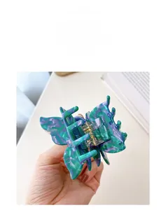 Detailed view of butterfly hair claw with emerald and violet marble pattern acetate texture