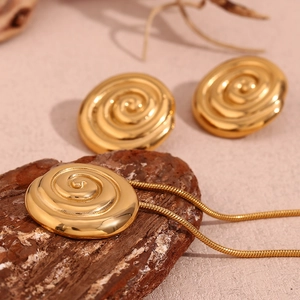 Close-up of golden spiral shell pendant and earrings set on dark wood texture background