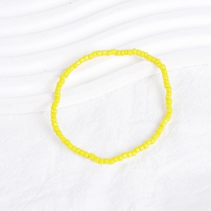 Detail of vibrant yellow seed bead elastic bracelet on textured white background