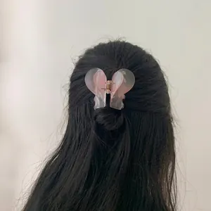 Detail of elegant pink translucent butterfly hair claw clip worn by a model in back view