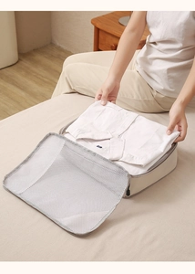 Travel compression organizer showing a hand folding a shirt into a breathable mesh bag