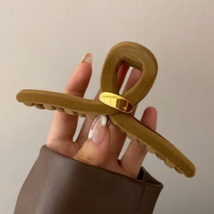 Détail de la grande pince à cheveux floquée en velours caramel avec plaque dorée chic