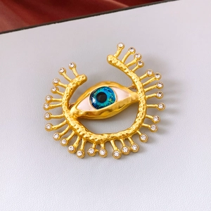 Macro detail of gold devil eye brooch with blue enamel and sparkling crystal eyelashes