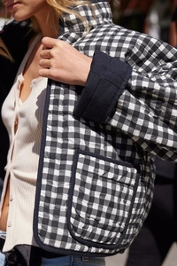 Detail of black and white gingham quilted jacket featuring contrast cuffs and front pocket