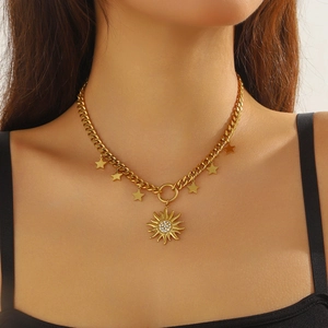 Detail of gold chain necklace with sun pendant and shimmering rhinestone star charms