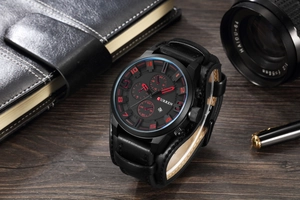 Mens chronograph watch with red markers on black dial placed on a dark wood background