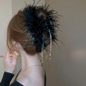 Detail of black feather hair claw with sparkling rhinestone tassels worn by a model