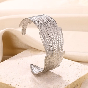 Detailed view of silver stainless steel feather bangle with textured engraving on stone base