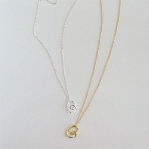 Detail of gold and silver minimalist spiral vortex pendant necklaces on fine O-chains