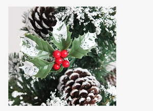 Macro detail of artificial snow on red berries, pine cones and holly leaves for Christmas