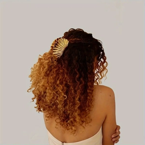 Detailed view of a golden metal shell hair claw clip holding a brunette bun hairstyle