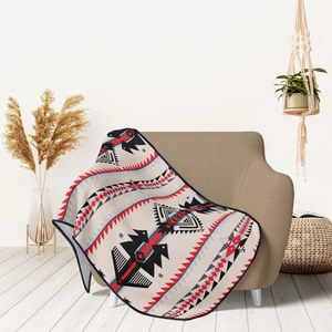 Close-up of flannel blanket with ethnic geometric tribal patterns on a brown fabric sofa