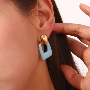 Detail of a geometric 18K gold-plated earring with light blue enamel on a model