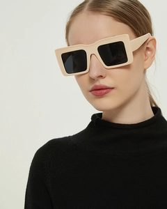Close-up of cream rectangular oversized sunglasses with dark lenses on a model