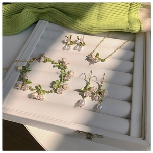 Detailed set of lily of the valley jewelry with green leaves and white pearls