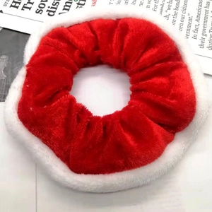Close-up of a festive red velvet Christmas scrunchie with white plush trim on a table