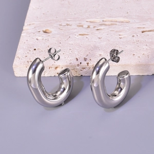 Detailed view of silver stainless steel C-shape earrings on a textured stone base