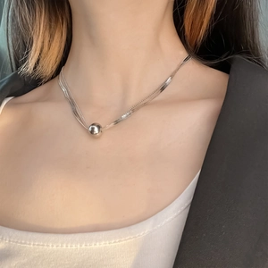 Detail view of double-layer silver ball pendant necklace with bead and snake chains