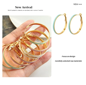 Detail view of large gold titanium hoop earrings with mint green, pink, and white enamel inlay