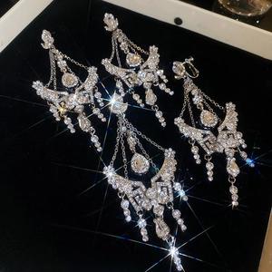 Macro shot of silver tassel earrings with crystal flowers and Greek fret patterns