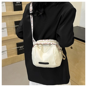 Detail of cream nylon crossbody bag with ethnic style embroidered wide strap and zipper