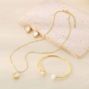 Detailed view of a gold-plated jewelry set with round zircon stones and a white pearl accent