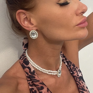 Detail showing vintage multi-layer pearl necklace and matching diamond earrings on a model
