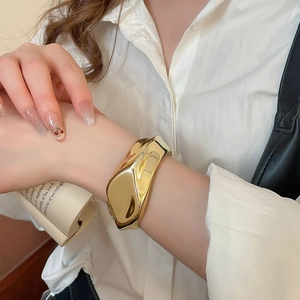 Detailed view of wide gold irregular crumpled cuff bracelet in molten metal style
