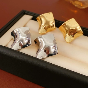 Détail de boucles d'oreilles carrées torsadées en or et argent sur coussin