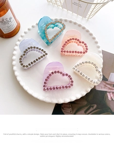 Detail of heart-shaped claw clips with rhinestones in various colors on a ceramic tray