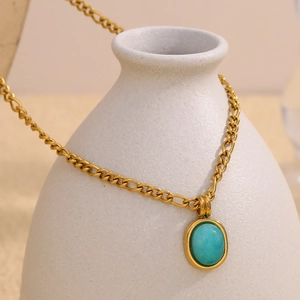 Dettaglio della catena placcata oro 18K con ciondolo in amazzonite su un vaso di ceramica