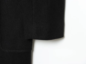 Close-up of premium black wool blend fabric texture and stitching on coat cuff
