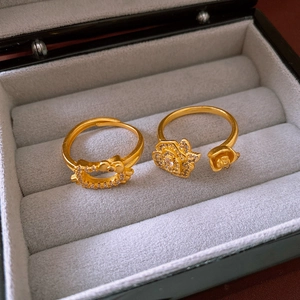 Detail of gold-plated open rings featuring a cat head profile and a blooming rose design