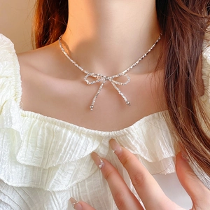 Gros plan d'un collier ras du cou avec nœud argenté sur la clavicule d'un mannequin
