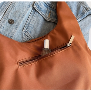 Detailed close-up of brown nylon hobo bag featuring silver metal front zipper pocket