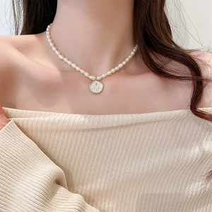 Dettaglio collana perle barocche con ciondolo cammeo floreale bianco dorato su modella