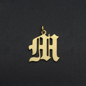 Close-up of Old English letter M pendant in gold plated stainless steel for DIY jewelry