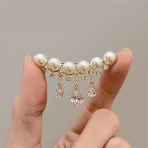 Detail einer eleganten Goldbrosche mit weißen Perlen, Kristallen und rosa Edelsteinen