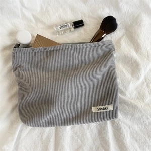 Minimalist grey corduroy makeup bag shown from above on a soft textured background