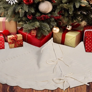 Detail of ivory knitted Christmas tree skirt with wavy edges and drawstring ties