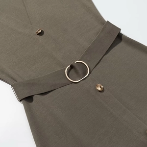 Detail of olive green midi dress featuring a golden circular buckle belt and woven texture