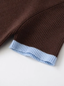 Detail eines schmal geschnittenen Strickpullovers mit braunem Stoff und blauen Rippbündchen