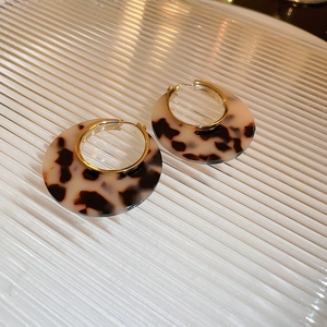 Chic tortoiseshell acrylic hoop earrings with gold metal accents on glass surface