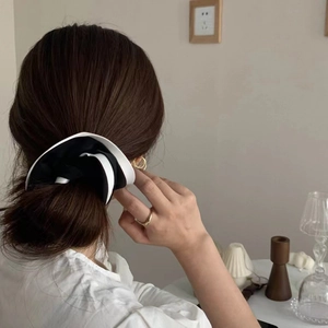 Elegant black and white contrast satin scrunchie worn by a model in a cozy home setting