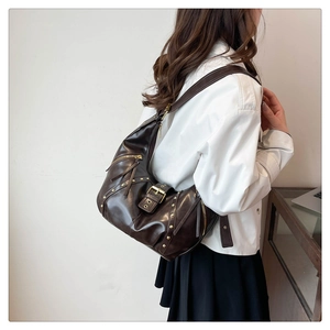 Detail der dunkelbraunen Vintage-Tasche mit goldenen Nieten und Y2K-Biker-Stil Ästhetik