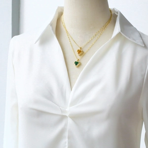 Detail of double-layer gold necklace with green and amber heart-shaped pendants
