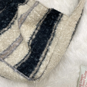 Macro view of plush black and white striped wool tote bag on soft white faux fur texture