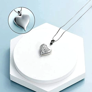 Silver cremation necklace with heart pendant and angel wings on a hexagonal stand