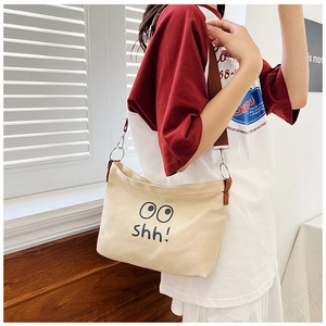 Detail of beige canvas shoulder bag with black eye graphic and adjustable strap