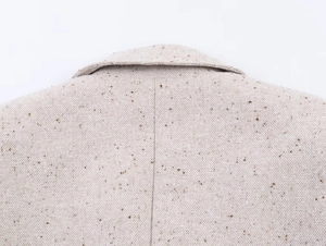 Gros plan détaillé de la couture du col et de la texture mouchetée du blazer beige